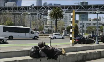  ?? AP PHOTO/ ERIC RISBERG ?? In this April 18 photo, a man rests and reads the Bible while sitting across the street from the proposed site of a homeless shelter in San Francisco.