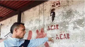  ??  ?? In memoriam: Jhorman Valero pointing to the image of his late cousin Bassil, stenciled on the terrace wall of his home in Guatire, Venezuela. — AP