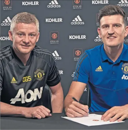  ??  ?? FICHADO. El central inglés Harry Maguire firma su contrato con el Manchester United al lado del entrenador del equipo, Ole