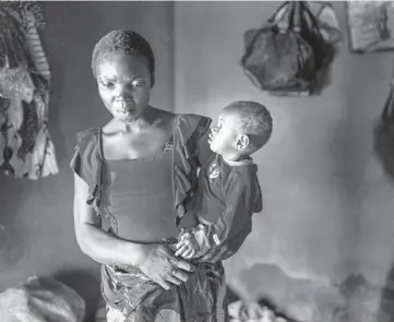  ?? JEROME DELAY/AP ?? Anayo Mbah, 29, holds one of her children in her home in Umuida, Nigeria, on Feb. 11. Mbah delivered her sixth child the same day she learned her husband died of COVID-19. His family stopped supporting her and sent her away weeks later.