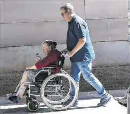  ?? Ricard Cugat ?? Un hombre empuja una silla de ruedas con una persona mayor.