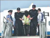  ?? MAO SIQIAN / XINHUA ?? A telecom fraud suspect gets off a plane escorted by police officers at Shenzhen Baoan Internatio­nal Airport in Guangdong province on Wednesday.