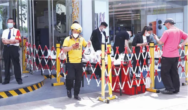  ?? Reuters ?? ↑
People pick up food deliveries at a collection point outside an office building during lunchtime in Beijing on Thursday.