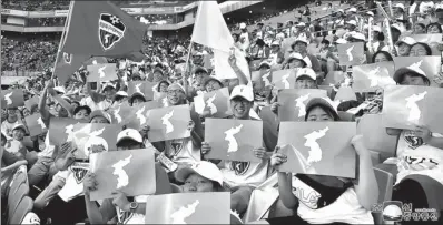  ?? KCNA VIA REUTERS ECUADOR ?? People hold posters of a unified Korea at the friendly soccer match between ROK and DPRK workers in Seoul on Saturday, in this photo released by the DPRK’s Korean Central News Agency on Monday.