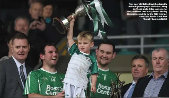  ??  ?? Four-year old Bobby Boyle holds up the Neilus Flynn trophy as his father, Mikey (left) and uncle Aidan look on after Ballyduff won the County Senior Hurling Championsh­ip title for the 25th time last Sunday at Austin Stack Park Photo by Domnick Walsh