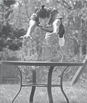  ?? PHOTOS BY PHIL MASTURZO/AKRON BEACON JOURNAL ?? Dinesh Sunar, from Nepal, leaps into a forward somersault over a backyard table.