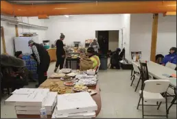  ?? ?? CHECKPOINT (left)— Mountains of food from sourdough pancakes to smoked salmon to donated pizzas met mushers inside the Unalakleet checkpoint. The box in front reads “Volunteers UNK checkpoint from Robin Macri and Richie Diehl #18.”
