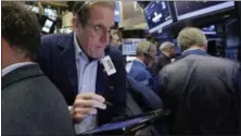  ?? RICHARD DREW — THE ASSOCIATED PRESS ?? Trader Luke Scanlon works on the floor of the New York Stock Exchange, Wednesday. Stock markets around the world made only modest moves on Wednesday, waiting to see what the White House has in store for U.S. tax policy.