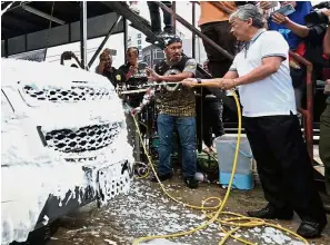  ?? — Bernama ?? Clean for a cause: Tengku Abdullah (right) washing a truck together with volunteers at the charity car wash.