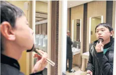  ??  ?? Chinese student Liu Yuxuan, 22, freshens his make-up in a restroom at a shopping mall in Shanghai.