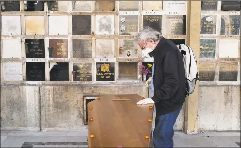  ?? Francois Mori / Associated Press ?? A man pays respect near the coffin of his wife who was 75 years old, during a funeral ceremony under the care of Paris undertaker Franck Vasseur, at Pere Lachaise cemetery in Paris on April 24, as a nationwide confinemen­t continues to counter the coronaviru­s.