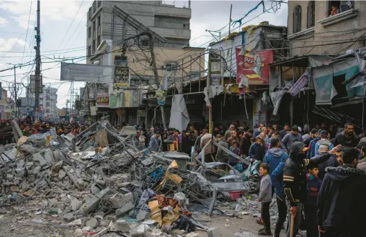  ?? FATIMA SHBAIR/AP ?? Palestinia­ns survey the destructio­n left in the aftermath of an Israeli strike Monday in Rafah, in the Gaza Strip.