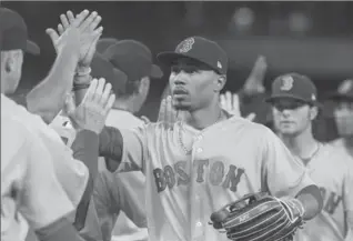  ?? FRED THORNHILL, THE CANADIAN PRESS ?? Red Sox outfielder Mookie Betts gets high-fives after clearing the bases with a double in the 10th to beat Toronto.