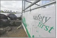  ?? (AP/Eugene Hoshiko) ?? A constructi­on fence featuring the words “Safety First” with a backdrop of the Olympic rings floating in the water in the Odaiba section in Tokyo. .