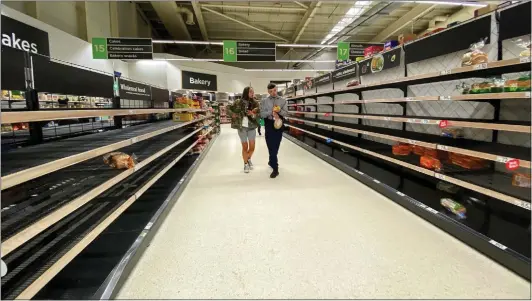  ??  ?? at Asda in Govan, Glasgow, wander down empty aisles after bulk-buying customers stripped shelves of essentials like bread