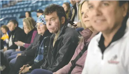  ?? MICHELLE BERG ?? Dave Repsher, centre, attends a Blades game Friday with his wife Amanda Repsher, left, and Dawg Nation Hockey Foundation's Marty Richardson, right. Repsher says hockey has been a big part of his recovery since he suffered burns to 90 per cent of his body in a 2015 helicopter crash.