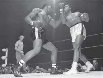  ?? THE ASSOCIATED PRESS/ FILES ?? Floyd Patterson, left, delivers a left hook to the chin of Muhammad Ali during their heavyweigh­t title fight, just one of the many thousands of punches to the head Ali took during his boxing career.
