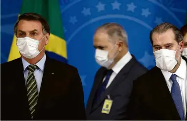  ?? Pedro Ladeira - 18.mar.2020/Folhapress ?? Jair Bolsonaro, Augusto Aras (ao fundo) e Dias Toffoli (à direita)