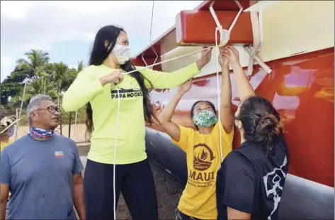  ??  ?? Faavae Maluia (from left) looks on as Kamehameha Maui junior Moani Atay, University of Hawaii graduate student Kala Tanaka and King Kekaulike senior Kuaola Emmsley precisely tie a new lashing on the Mo‘okiha O Pi‘ilani Saturday. “I’m showing them how to lash the canoe,” Maluia said. “All the lashings are different. It’s more like an art than anything else.” Tanaka supervised the girls when they took part in the Papa Ho’okele program in 2019, and they have continued to volunteer with the voyaging canoe, as well as learn about sailing and celestial navigation. Maluia said the goal is to return the canoe, first launched in 2014 to the sea, for interislan­d voyages in 2021.