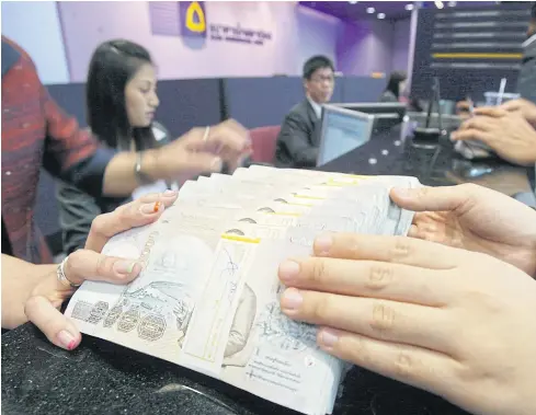  ?? PHRAKRIT JUNTAWONG ?? A client deposits money at Siam Commercial Bank. The Bank of Thailand says foreign investors regard Thai assets as a safe haven, giving strength to the baht.