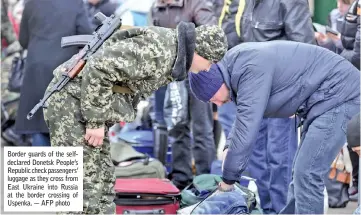  ??  ?? Border guards of the selfdeclar­ed Donetsk People’s Republic check passengers’ luggage as they cross from East Ukraine into Russia at the border crossing of Uspenka. — AFP photo