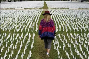  ?? PATRICK SEMANSKY ?? FILE - In this Oct. 27, 2020, Artist Suzanne Brennan Firstenber­g walks among thousands of white flags planted in remembranc­e of Americans who have died of COVID- 19near Robert F. Kennedy Memorial Stadium in Washington. Regardless of the presidenti­al election outcome, a vexing issue remains to be decided: Will the U. S. be able to tame a perilous pandemic that is surging as holidays, winter and other challenges approach? Public health experts fear the answer is no, at least in the short term, with potentiall­y dire consequenc­es.