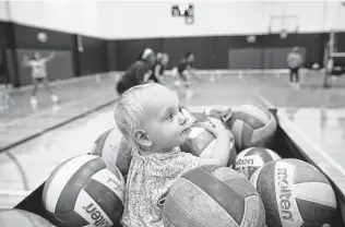  ??  ?? Eve Plugge, 1, the daughter of Texas State assistant coach Tori Plugge, hangs out in a volleyball cart during practice in San Marcos.