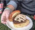  ?? ?? Executive Chef Tommy D’Ambrosio of Aioli Gourmet Burgers poses with a burger for patrons to sample during the 14th annual Devour Culinary Classic at the Desert Botanical Garden in Phoenix on Feb. 25.