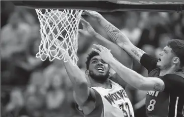  ?? JEFF WHEELER/TRIBUNE NEWS SERVICE ?? Timberwolv­es center Karl-Anthony Towns (32) takes aim for a fourth quarter shot while defended by Miami Heat guard Tyler Johnson (8) on Monday in Minneapoli­s, Minn.