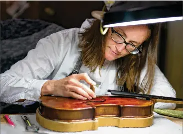  ?? PHOTOS CONTRIBUTE­D BY JASON GETZ ?? Beau Vinci Violins luthier Sally Mullikin works on the assembly of a new violin at the shop in Alpharetta. Luthiers are the trained experts who build and repair violins.