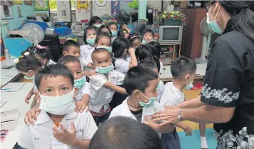  ??  ?? ABOVE Kindergart­en students at a childdevel­opment centre in Wat King Kaew in Samut Prakan’s Bang Phli district wear masks as they suffer the stench from about 200 pigs kept nearby in the temple’s compound.