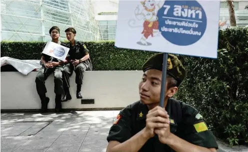  ?? Foto: AFP/Lillian Suwanrumph­a ?? Studenten machen Pause vom Militärdie­nst, um für die Stimmabgab­e zu werben.