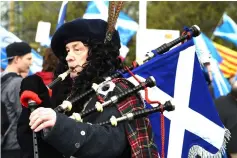  ??  ?? A pro-independen­ce demonstrat­or with Saltire flags, the national flag of Scotland, plays the bagpipes after a march in support of Scottish independen­ce, through the streets of Glasgow. — AFP photo