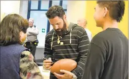  ?? ANGELA BRANDT U-T COMMUNITY PRESS ?? Super Bowl champion Eric Weddle signs a football for fans after a proclamati­on was read in his honor at the Poway City Council meeting Tuesday night.