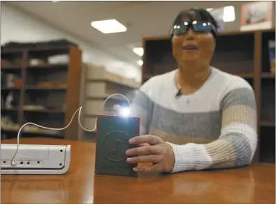  ?? AP photo ?? Minh Ha, assistive technology manager at the Perkins School for the Blind tries a LightSound device for the first time at the school’s library in Watertown, Mass., on March 2. As eclipse watchers look to the skies in April, new technology will allow people who are blind or visually impaired to hear and feel the celestial event.