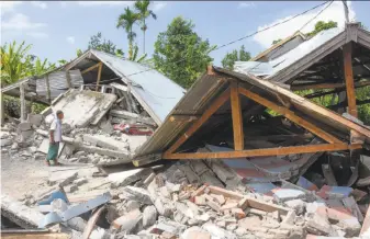  ?? Aulia Ahmad / AFP / Getty Images ?? A resident examines the remains of houses destroyed by the quake on the Indonesian island of Lombok. The temblor also triggered a large landslide from Mount Rinjani, an active volcano.