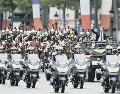  ??  ?? Macron waves to crowds as he is transporte­d up the Champs-Elysees Avenue yesterday.