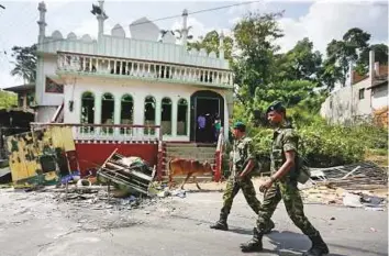  ?? Reuters ?? ■ Sri Lanka’s Special Task Force soldiers walk past a damaged mosque after a clash between two communitie­s in Digana, central district of Kandy, Sri Lanka on March 8.
