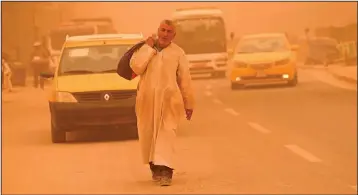  ?? ?? A man walks on a street during a sandstorm.