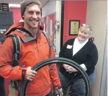  ?? MEGAN GILLIS ?? Cameron Smedley shows off a bike wheel he bought while Heartwood staffer Moe Moloughney looks on at the OC Transpo Lost and Found sale Saturday at Heartwood House.