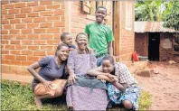  ?? ALEXIS MACDONALD PHOTO ?? Monica, centre, with her grandchild­ren in Jinja, Uganda. Monica, living with HIV, was tasked with caring for her grandchild­ren after their parents died of HIV/AIDS. Her community helped build her a new house that went to grandchild­ren after her death.