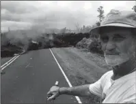  ?? The Associated Press ?? ROAD CLOSED: Resident Sam Knox, 65, rides his bicycle to the edge of lava burning across the road on Saturday in the Leilani Estates in Pahoa, Hawaii. Hundreds of anxious residents on the Big Island of Hawaii hunkered down Saturday for what could be...