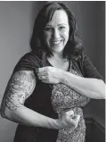  ?? Eric Gay / Associated Press ?? MJ Hegar pulls up her sleeve to reveal part of a tattoo that winds around her arm and back to cover scars from a shrapnel wound.