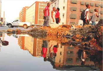  ?? Picture by Tawanda Mudimu ?? People walk past a pool of treated water gushing from a burst pipe at the corner of Julius Nyarere Way and Nelson Mandela Avenue in Harare yesterday. —