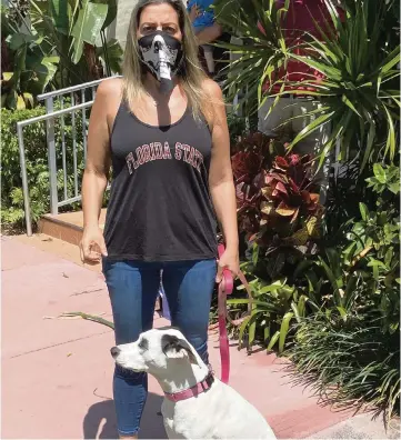  ?? Courtesy to the Miami Herald ?? Monica Matteo Salinas, a South Beach resident, wears a Halloween mask to walk her 3-year-old mixed-breed dog Luna.
