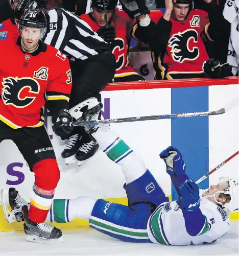  ?? THE CANADIAN PRESS ?? Troy Brouwer of the Flames rocks Brock Boeser during Saturday’s contest in Calgary. The Canucks rookie is on pace for a 44-goal campaign but opposing teams are starting to pay him special attention — taking away his time and space to operate— says...