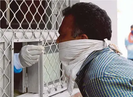  ?? AFP PIC ?? A medical worker collecting a swab sample from a man for a Rapid Antigen Test for the Covid-19 coronaviru­s at a government health centre in New Delhi yesterday.