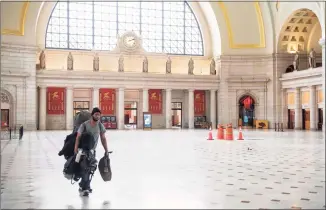  ?? Nicholas Kamm / AFP via Getty Images ?? In this file photo taken on May 22, a man carries his bags through the main hall of Union Station in Washington, D.C. The U.S. Centers for Disease Control and Prevention cautioned Americans on Thursday against traveling for the Thanksgivi­ng holiday next week, as the coronaviru­s spreads out of control.