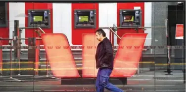  ?? File/agence France-presse ?? ↑
A man walks past a sign of Westpac in Melbourne, Australia.