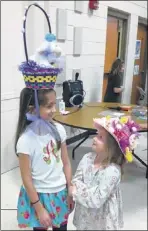  ??  ?? First place winner, Ava Evans, 8, and third place winner, Page Coburn, 5, check out each other’s Easter bonnets during Colliervil­le United Methodist Church’s Easter Bonnet contest.